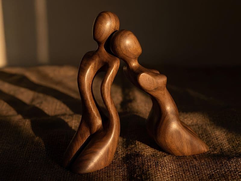 Zwei aneinandergelehnte Holzfiguren im warmen Abendlicht